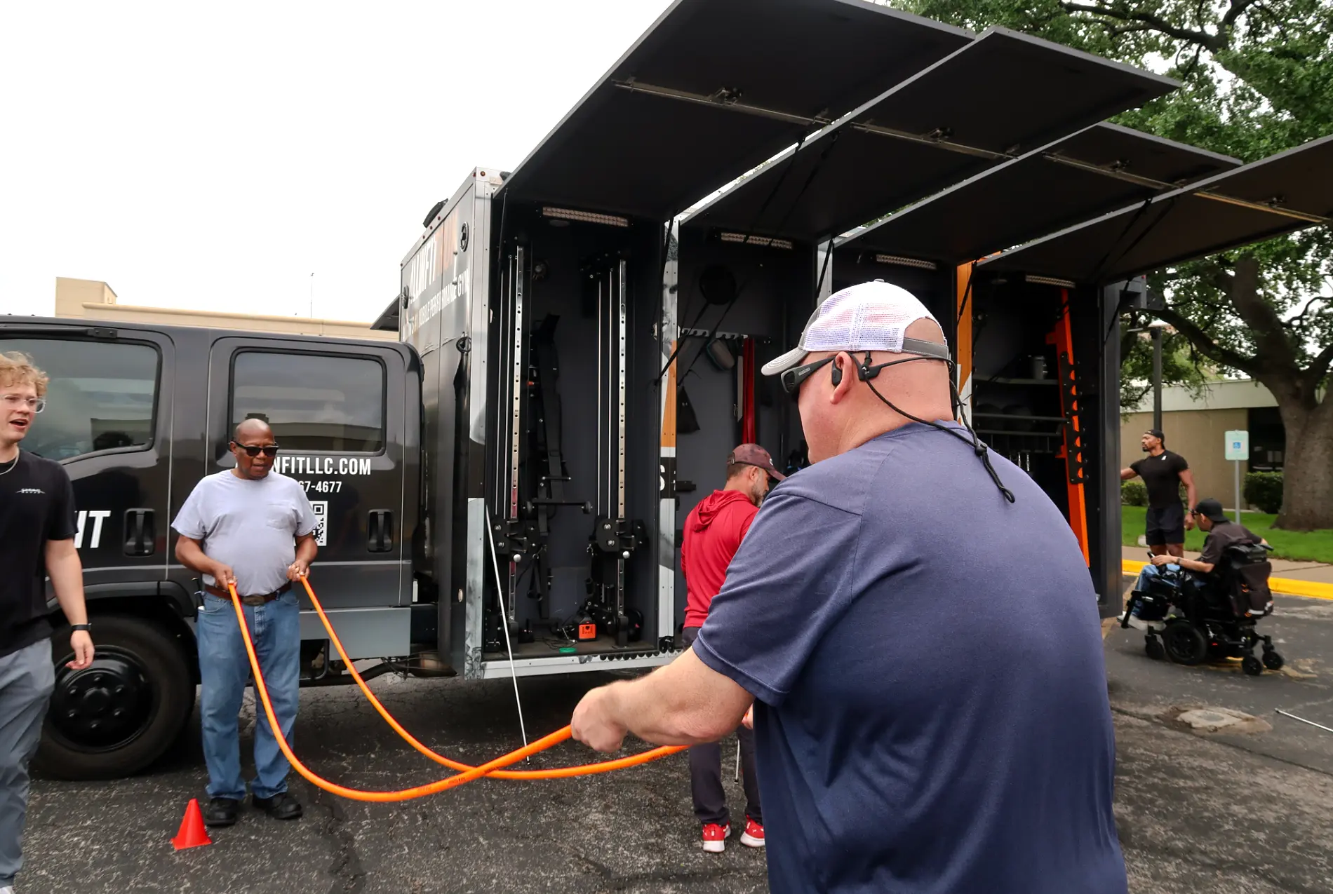 Participants using an adaptive training rope beside the mobile gym